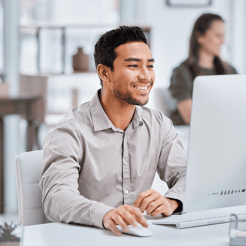 Un ragazzo sorride cliccando sul mouse e lavorando al suo laptop